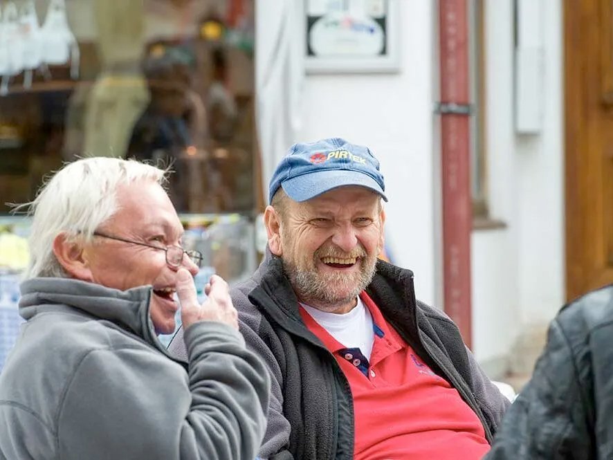 drei Männer sitzen auf der Terasse haben Spaß und lachen sehr